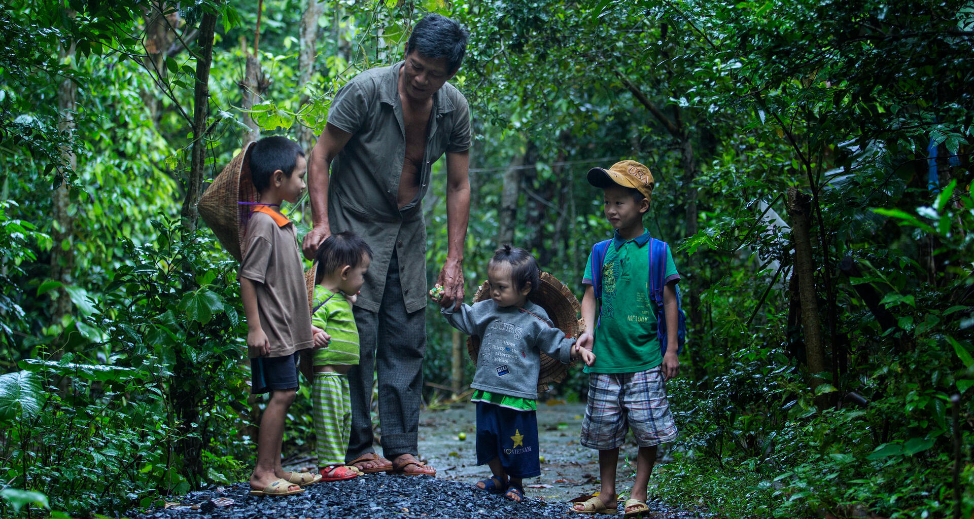 A man holds hands with children.